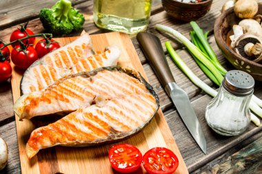 Somon ızgara biftek çeşitli sebze ve baharatlar ile. Ahşap bir arka plan üzerinde.