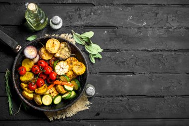 Otlar ile tavada ızgara sebze. Siyah bir rustik arka planda.