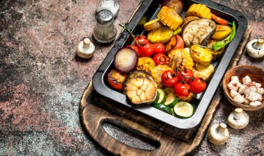 Bir tavada ızgara kavrulmuş sebze ve mantar. Rustik bir arka plan üzerinde.