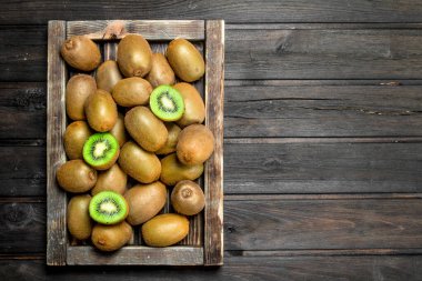 Olgun kivi içinde ahşap tepsi. Ahşap arka plan üzerinde