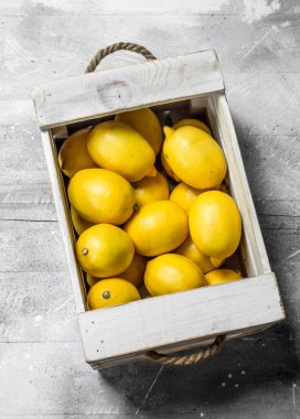 Ahşap kutusunda taze sarı limon. Rustik arka plan üzerinde