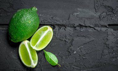 Taze limon ve bir bütün kireç parçaları. Rustik siyah arka plan üzerine