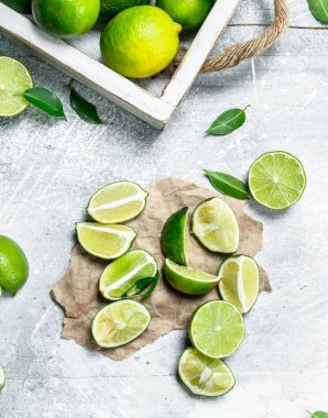 Taze limon kağıt tepsisi ve kireç dilimleri üzerinde. Rustik arka plan üzerinde