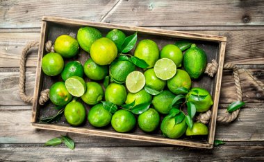 Taze yeşil limes yaprakları bir tepsi ile. Ahşap arka plan üzerinde