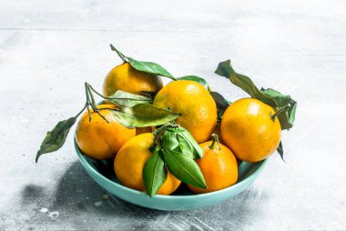 Yaprakları bir kase ile taze mandalina. Beyaz rustik arka plan üzerinde