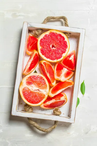 stock image Juicy pieces of grapefruit on a tray. On rustic background