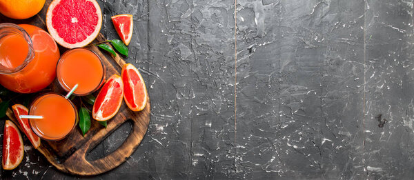 Juice of ripe grapefruit in a jug on a cutting Board. On rustic background