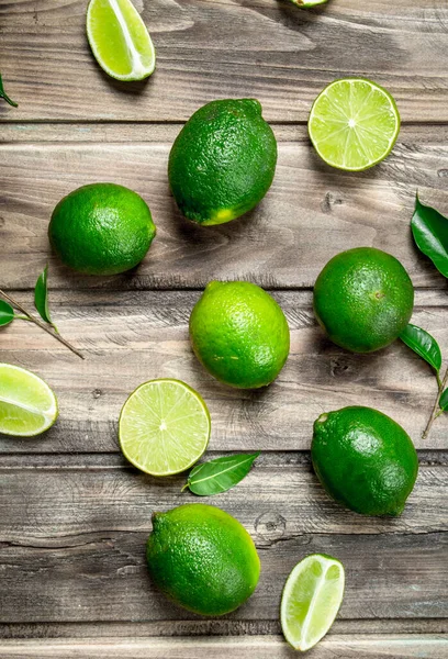 Geheel Stukken Van Verse Limoen Met Bladeren Houten Achtergrond — Stockfoto