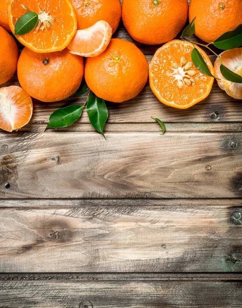 stock image Halves and whole mandarins. On wooden background