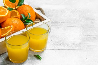 Portakal suyu bir bardak ve taze portakal içinde belgili tanımlık tepsi. Rustik arka plan üzerinde