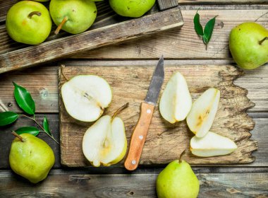 Taze armut tepsi ve tahta bıçak ile kesme üzerinde dilimlenmiş armut. Ahşap arka plan üzerinde