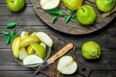 Bir bıçak ile kesme tahtası üzerinde bir kapta taze armut parçaları. Ahşap arka plan üzerinde