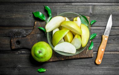 Bir bıçak ile kesme tahtası üzerinde bir kapta taze armut parçaları. Ahşap arka plan üzerinde