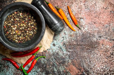 Taze biber harç havaneli ve acı biber bir elmanın yarısı. Rustik arka plan üzerinde