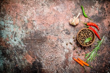 Acı biber, sarımsak ve biberiye ile bir kapta kokulu biber bezelye. Rustik arka planda