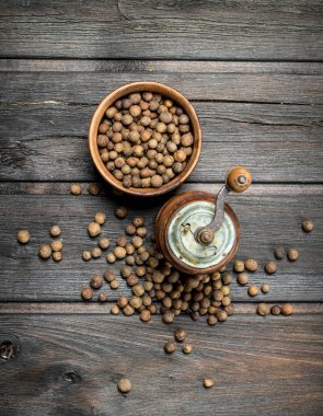 Kase ve biber öğütücü biber bezelye. Siyah ahşap arka plan üzerinde