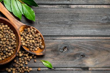 Kaşık ve Defne yaprakları ile kase karabiber bezelye. Ahşap arka planda