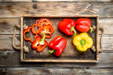 Parçalar ve tepside bir bütün olgun tatlı biber. Ahşap arka planda