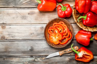 Tatlı biber kase bıçak ve sepet içinde biber dilimlenmiş. Ahşap arka plan üzerinde