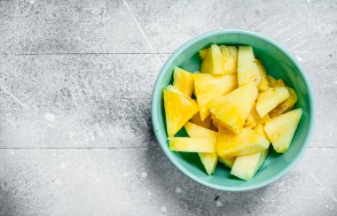 Bir kase içinde olgunlaşmış ananas parçaları. Beyaz rustik arka plan üzerinde