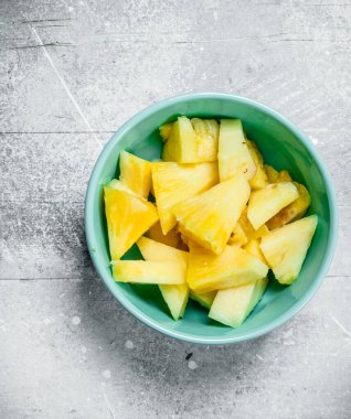 Bir kase içinde olgunlaşmış ananas parçaları. Beyaz rustik arka plan üzerinde