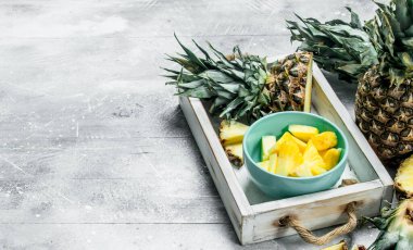 Tepsiye bir kase kokulu olgun ananas. Rustik arka plan üzerinde