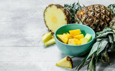 Bir kase taze ananas ve olgun ananas parçaları. Beyaz rustik arka plan üzerinde