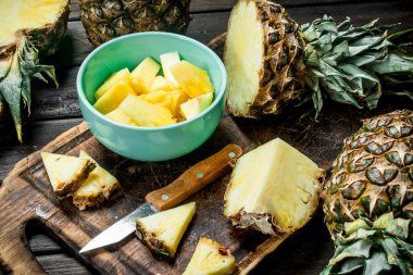 Bir kase ve bir bıçak ile kesme tahtası üzerinde bir ananas kesme. Ahşap arka plan üzerinde
