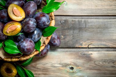 Yarısı ve sepet yaprakları ile bütün Erik. Ahşap arka plan üzerinde