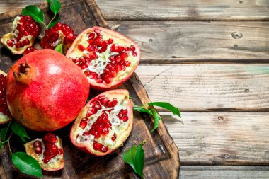 Kesme tahtası yapraklarda ile taze nar parçaları. Ahşap arka plan üzerinde