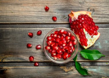 Nar taneleri cam kase içinde. Ahşap arka plan üzerinde