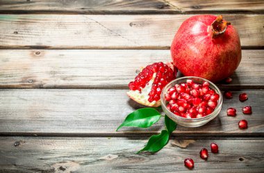 Kase ve yaprakları ile sulu nar nar taneleri. Ahşap arka plan üzerinde