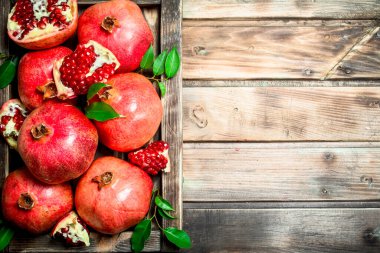 Tepside yaprakları ile kokulu olgun nar. Ahşap arka planda