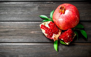 Bütün ve yaprakları ile olgun nar parçaları. Ahşap arka plan üzerinde