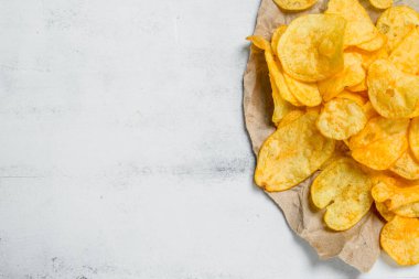 Patates cipsi kağıt üzerinde. Beyaz rustik arka plan üzerinde.