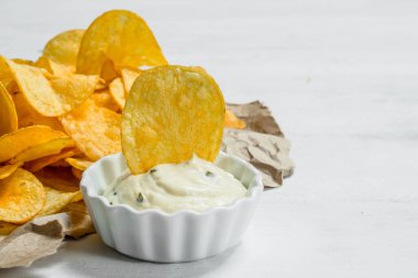 Soslu patates cipsi. Beyaz rustik arka plan üzerinde.