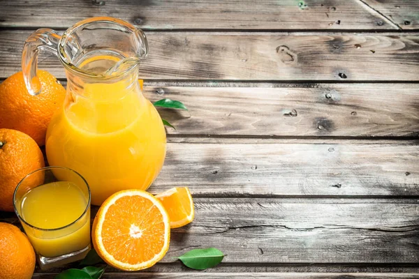 stock image Orange juice in the pitcher. On wooden background