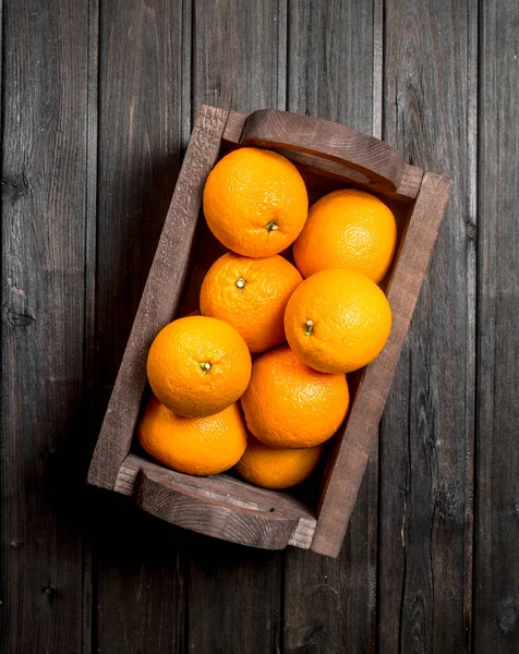 ボックスでジューシーなオレンジ 黒の木製の背景に — ストック写真