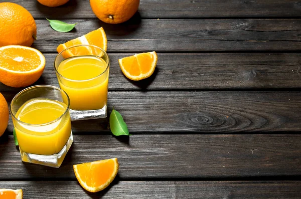 stock image Orange juice in a glass of fresh oranges. On wooden background