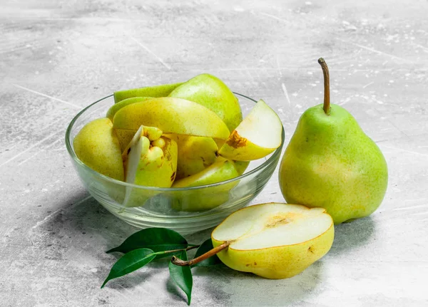 stock image Pieces of fresh pears in bowl with leaves. On white rustic background