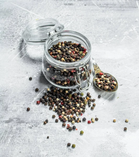エンドウ豆は ガラスの瓶にスプーンでコショウします 白い素朴な背景に — ストック写真