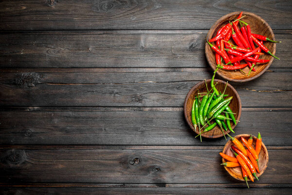 Красный, зеленый, оранжевый перец в миске. На черном фоне
