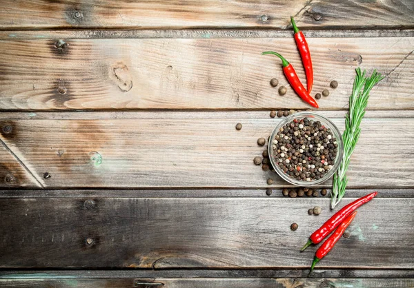 stock image Black pepper peas in a glass bowl and fresh red pepper. On wooden background