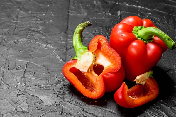 stock image Pieces of and a host sweet pepper. On black rustic background