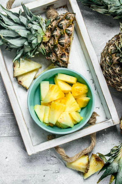 Tepsi üzerinde bir kapta taze ananas parçaları. Rustik arka plan üzerinde