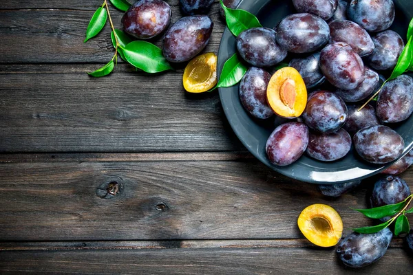 stock image Fragrant plum in a plate. On wooden background