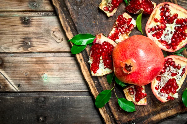 Stücke Frischen Granatapfels Mit Blättern Auf Dem Schneidebrett Auf Holzgrund — Stockfoto