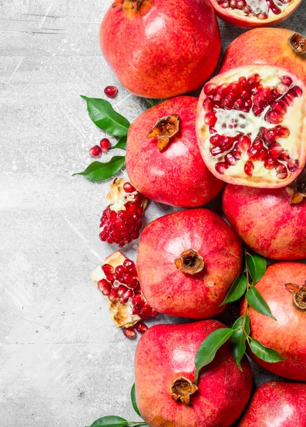 stock image Ripe pomegranates with leaves. On white rustic background