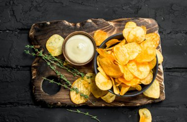 Sos ve kekik kase patates cipsi. Rustik siyah arka plan üzerine.