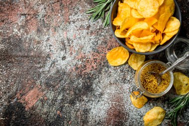 Fransız hardalı ve biberiye patates cipsi. Rustik bir arka plan üzerinde.